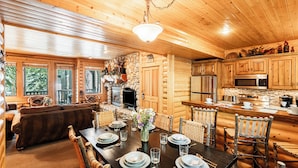 A log cabin interior with a dining area, kitchen, and living room. - World-class Ski spot + Year-round Pool & Hot Tub! (Park City)