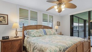 A bedroom with a large bed, two bedside tables, a ceiling fan, and a window with blinds. - 2/2 Corner Unit Condo in Bonita Bay! Large Lanai Space! (Bonita Springs)