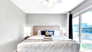 Une chambre d’hôtel avec un grand lit, une tête de lit, deux lampes de chevet et une vue sur l’extérieur grâce à une grande fenêtre.