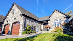 A stone building with a garage, a covered entryway, and a well-maintained lawn. - Creekside Bed & Breakfast Niagara Falls (Niagara Falls)