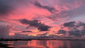 Ein Sonnenuntergang über ruhigem Wasser, im Vordergrund ein Yachthafen.