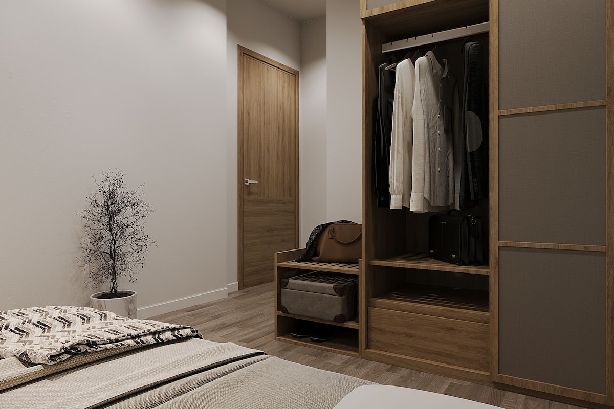 A bedroom with a wooden wardrobe, a bed with a patterned blanket, and a small plant.