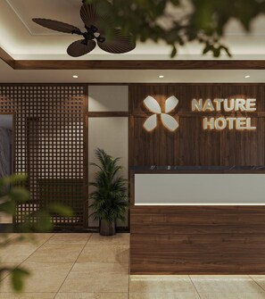 En receptionsdisk med träpanel och en skylt med texten ”NATURE HOTEL”.