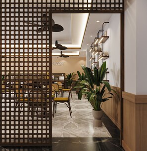 A modern interior with a dining area, a reception desk, and a staircase. - Nature Hotel (Xuan Huong - Da Lat)