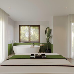 A modern bathroom with a freestanding bathtub, a large window with blinds, a potted plant, and a tray with toiletries. - Nature Hotel (Xuan Huong - Da Lat)