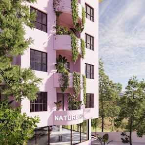 A multi-story building with balconies covered in greenery, a sign reading "NATUREHOTEL", and a clear view of trees and mountains in the background. - Nature Hotel (Xuan Huong - Da Lat)