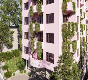 A multi-story hotel with balconies covered in greenery, a clear sky, and a paved ground area. - Nature Hotel (Xuan Huong - Da Lat)