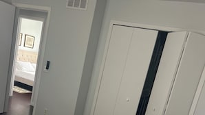 Une chambre à coucher comprenant un lit, une armoire et une porte donnant sur une autre pièce.