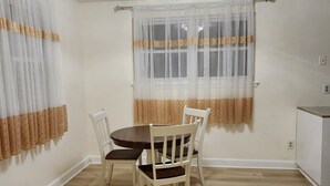 A dining area with a round table and four chairs, a window with sheer curtains, and a ceiling light fixture. - Convenient/family friendly home with yard driveway

 (Silver Spring)