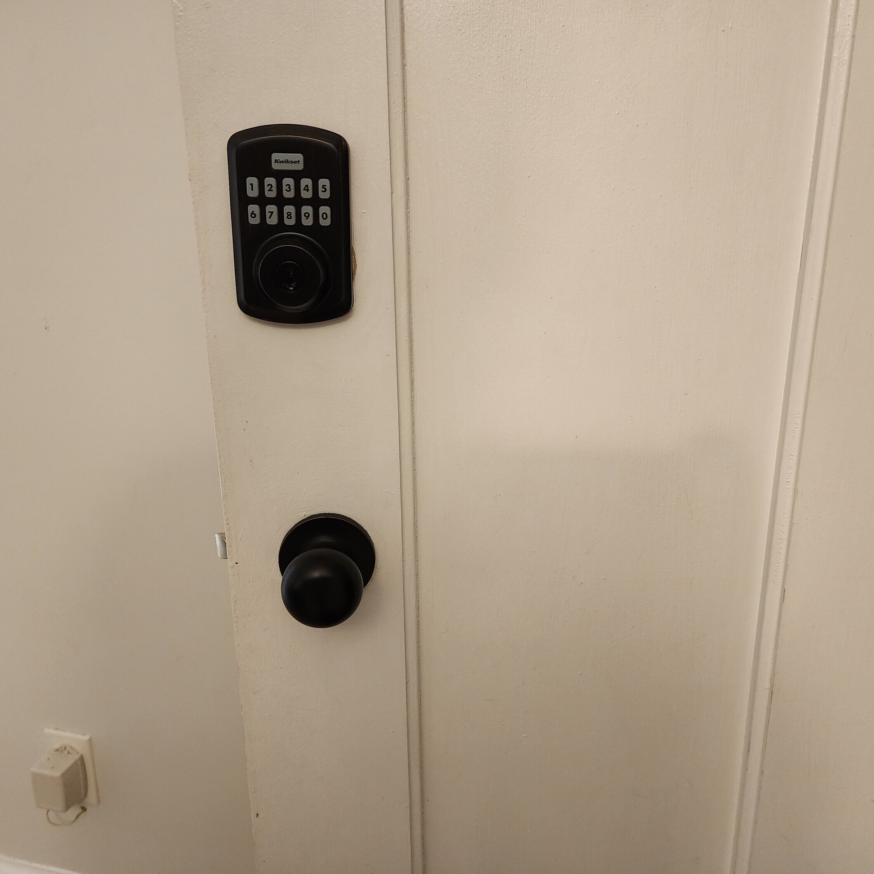 Een deur met een Kwikset keypad-slot en een ronde deurklink.