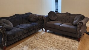 A living room with two dark-colored sofas, a beige carpet, and a door leading to another room. - Convenient/family friendly home with yard driveway

 (Silver Spring)