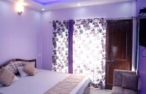A bedroom with a bed, a chair, and a wooden door. - Eden Hotel & Resort Shimla (Shimla)