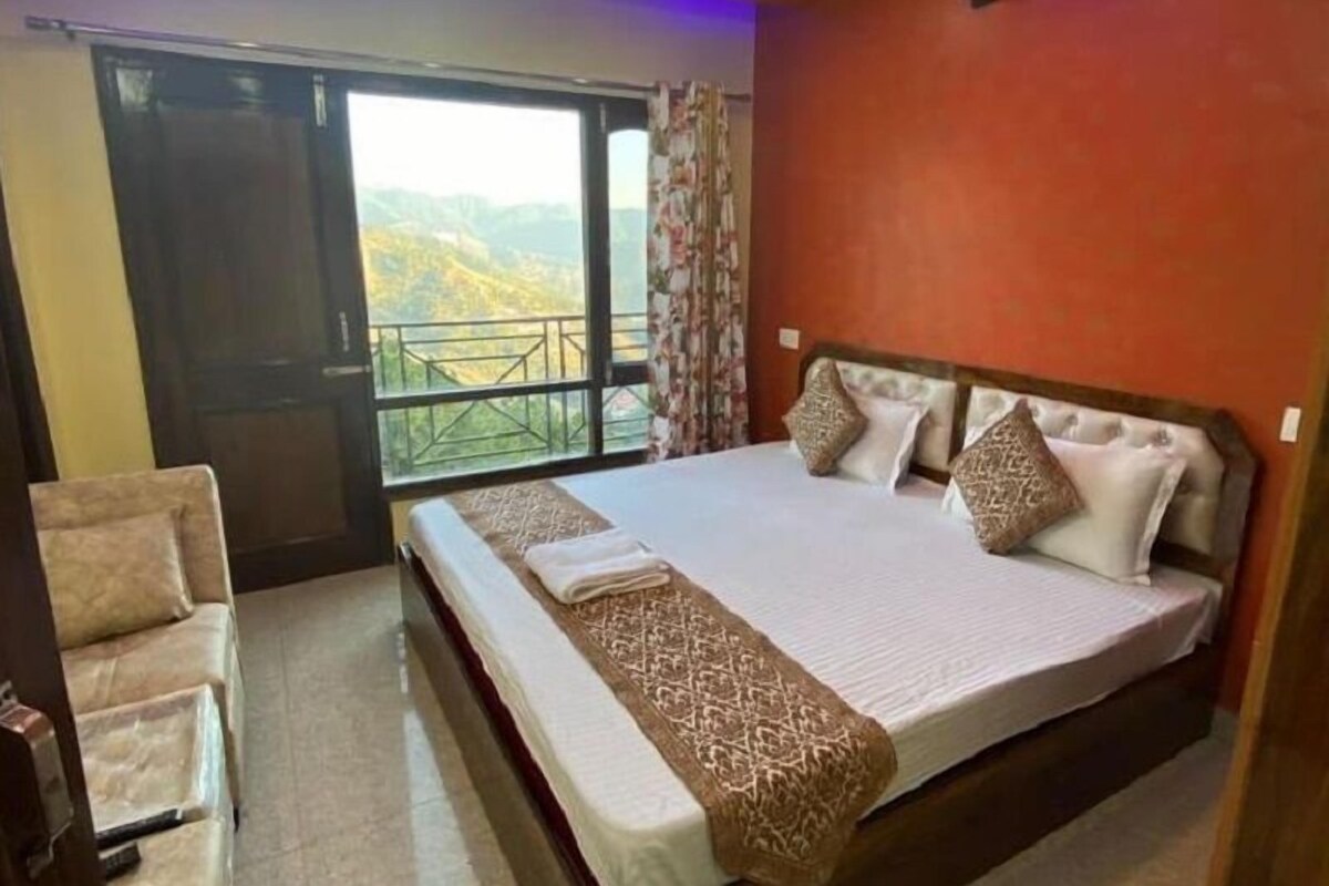 Une chambre avec un grand lit, une chaise et un balcon offrant une vue sur les montagnes.