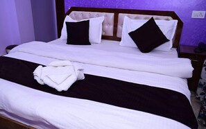A neatly made bed with white and black bedding, a folded towel, and a wooden headboard. - Eden Hotel & Resort Shimla (Shimla)