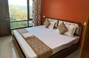 A bedroom with a large bed, a view of mountains through a balcony, and a wooden headboard. - Eden Hotel & Resort Shimla (Shimla)
