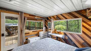 A bedroom with a large bed, a desk, and a view of the outdoors.
