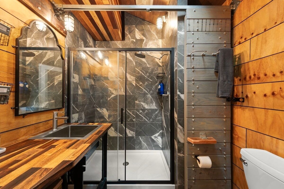 Un bagno moderno con un mobile bagno in legno, un box doccia in vetro e un water.