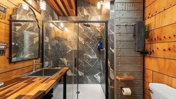 Un bagno moderno con un mobile bagno in legno, un box doccia in vetro e un water.