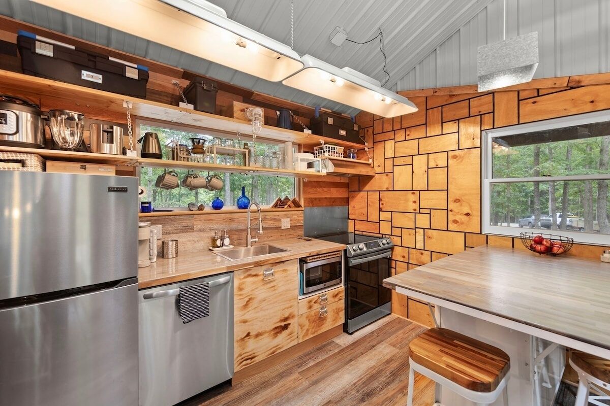 A modern kitchen with wooden accents, stainless steel appliances, and a large window offering a view of the outdoors.