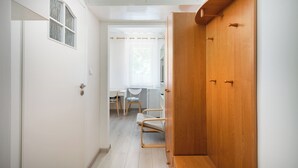 Un couloir avec une armoire en bois, une porte avec une fenêtre et un bureau avec des chaises.