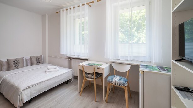 Une chambre à coucher comprenant un lit, deux bureaux, des chaises, un radiateur et un téléviseur.