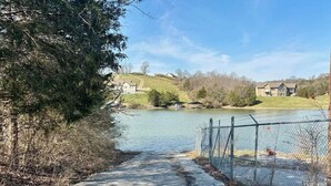 A concrete pathway leading to a lake with houses in the background.