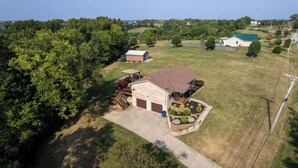Une maison de plain-pied avec un garage, un patio couvert et un jardin aménagé.