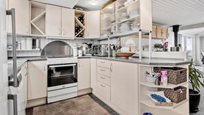 Une cuisine moderne avec des meubles blancs, un four encastré, une cuisinière en acier inoxydable et un grand îlot central doté d’un évier.
