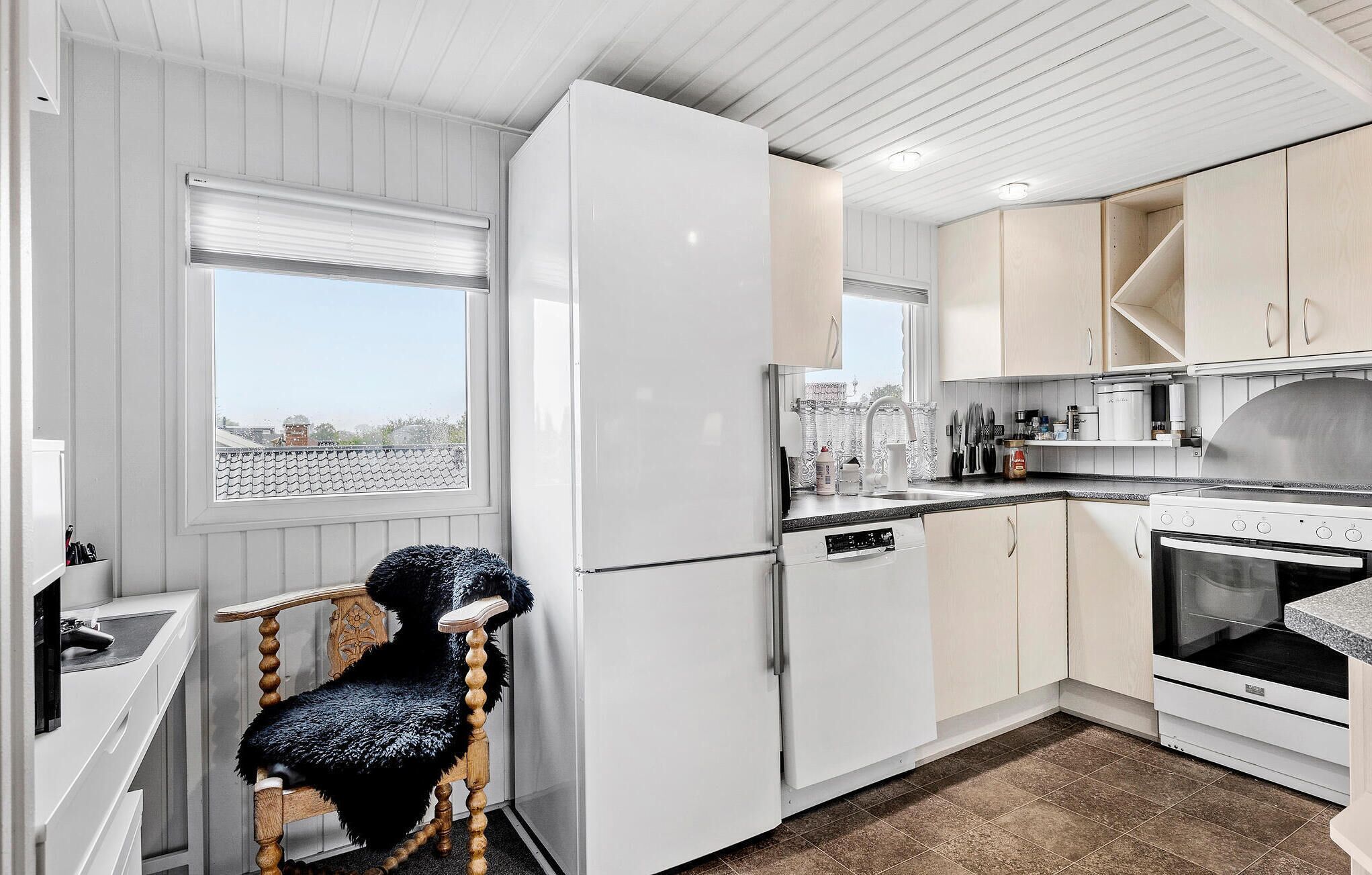 Ett modernt kök med vita skåp, en inbyggd ugn och ett fönster med utsikt över stadsbilden.