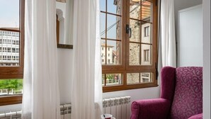 A room with a window, a radiator, a chair, and a small table with a cup.