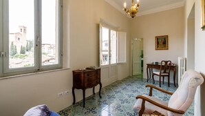 Une pièce dotée d’une grande fenêtre, d’un lustre, d’une table à manger avec des chaises et d’un sol à motifs.