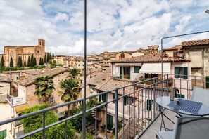 Un balcón con mesa y sillas, con vistas a un pueblo histórico con edificios y una iglesia.