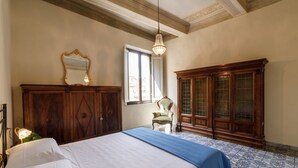 Une chambre à coucher avec un lit, une armoire en bois, une chaise et un miroir.