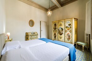 Een slaapkamer met een bed, een dressoir, een spiegel en een kroonluchter.
