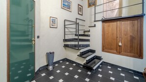 A staircase with black and white checkered flooring, a green door, and a wooden cabinet.