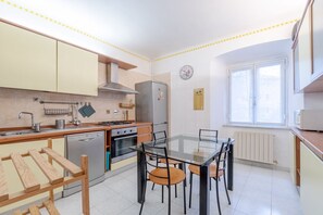 Cocina compacta con mesa de comedor, electrodomésticos integrados y ventana.