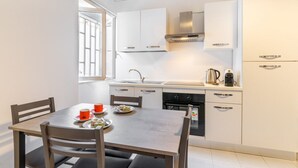 Una cocina moderna con armarios blancos, una campana extractora de acero inoxidable y un comedor con mesa y sillas.