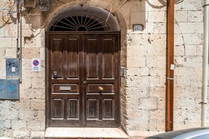 A large wooden door with a metal arch above it, set in a stone wall.