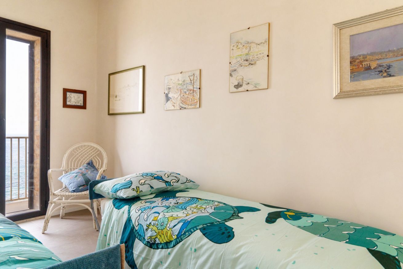 A bedroom with two beds, a chair, and wall art.