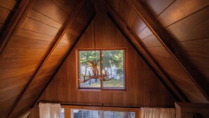 Een kamer met houten lambrisering, een kroonluchter en een raam met uitzicht op bomen.