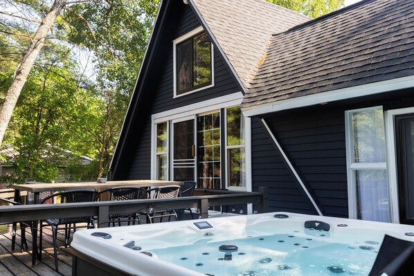 Une maison dotée d’un jacuzzi, d’une terrasse et de mobilier d’extérieur.