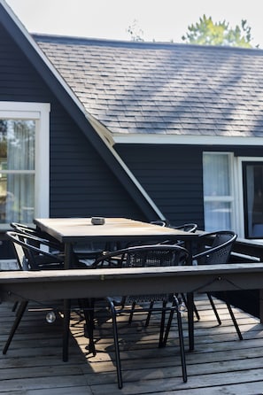 Une terrasse en bois avec une table et des chaises, une fenêtre et une porte.