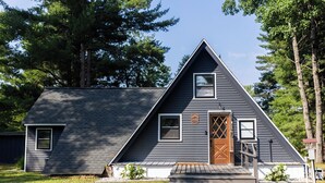 Een driekantig huis met een houten deur en een klein voortuintje.