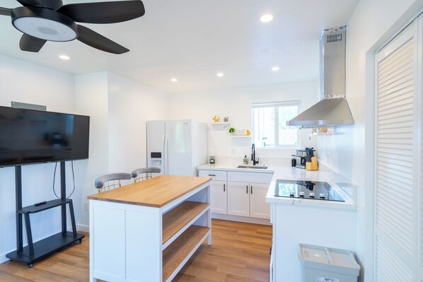 A modern kitchen with white cabinets, a wooden countertop, a built-in oven, and a ceiling fan. - Charming and Stylish Guesthouse (Phoenix)