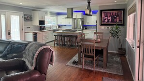 A modern kitchen with white cabinets, a central island, and a dining area with wooden chairs. - Desert Oasis with in ground pool, 4 bedrooms, 3 baths in the heart of Yakima! (Yakima)