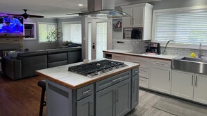 A modern kitchen with grey cabinets, a central island with a stove, and a microwave above the sink. - Desert Oasis with in ground pool, 4 bedrooms, 3 baths in the heart of Yakima! (Yakima)