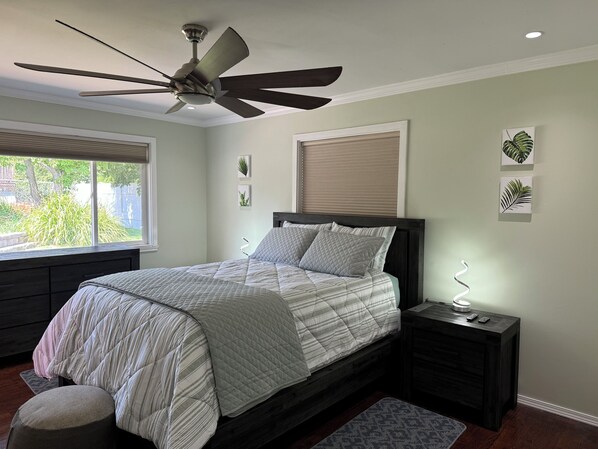 A bedroom with a bed, a ceiling fan, a bedside table with a lamp, and a window with blinds. - Desert Oasis with in ground pool, 4 bedrooms, 3 baths in the heart of Yakima! (Yakima)