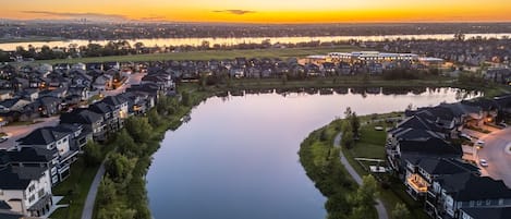 A residential area with houses, a lake, and a sunset.