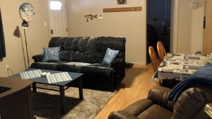 A living room with a dark-colored sofa, a striped coffee table, and a wooden dining table with chairs. - Sea Shell Inn. A cozy hideaway (Duncan)
