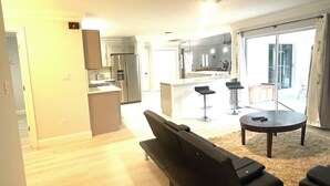 Un salon moderne avec un canapé, une table basse et une vue sur la cuisine et l’espace repas.